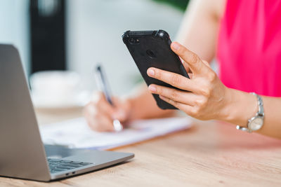 Midsection of woman using mobile phone on table