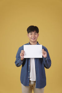 Portrait of smiling boy standing against yellow background