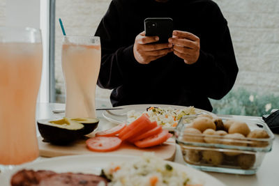 Midsection of man using mobile phone while sitting on table