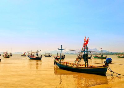 Fishing boats moored in sea against clear sky