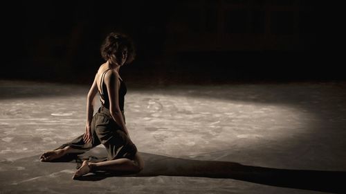 Full length of young woman dancing in darkroom