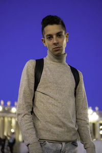 Portrait of young man standing against blue sky