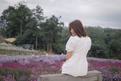 Rear view of woman sitting on retaining wall