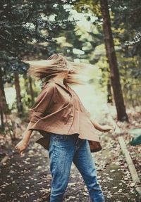 Woman shaking head while standing on land in forest