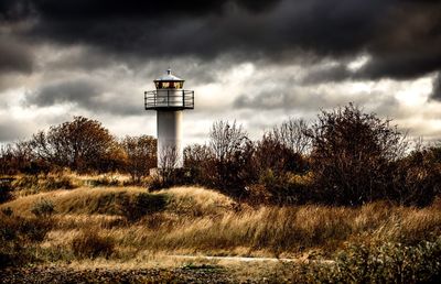 Lighthouse on landscape against sky
