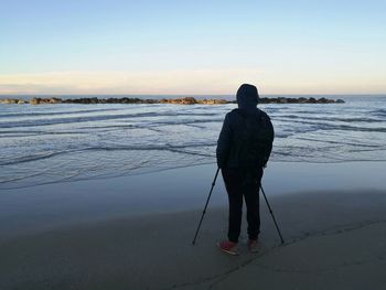 Rear view of photographer standing at beach against sky