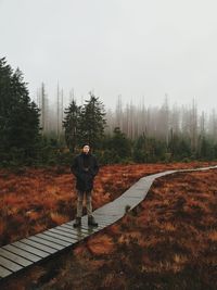 Man standing on dirt road against sky