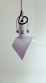 Close-up of electric lamp hanging against white background