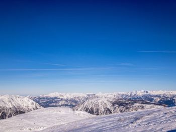 Snow covered landscape against blue sky