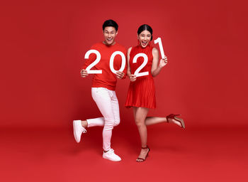 Portrait of young couple against red background