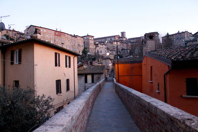 Footpath amidst buildings in town against clear sky