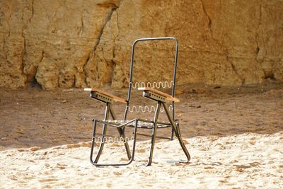 Empty chair on sand against wall