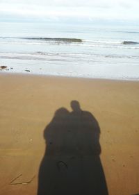 Shadow of man on beach against sky