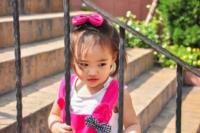 Cute girl standing against railing