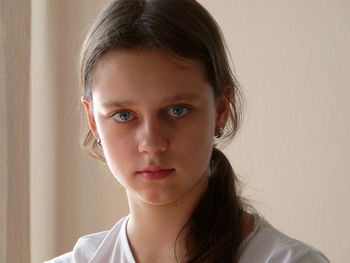 Close-up portrait of woman staring against wall at home