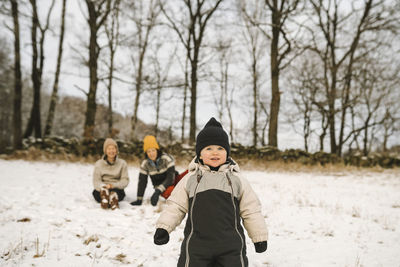 Girl wearing knit hat looking away while standing on snow