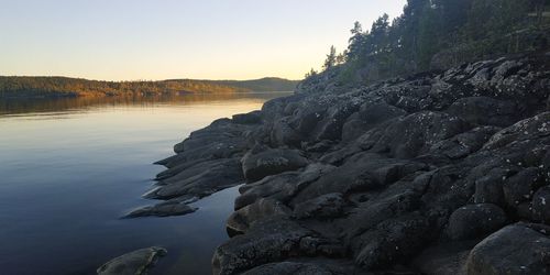 Rocks on shore against sky during sunset