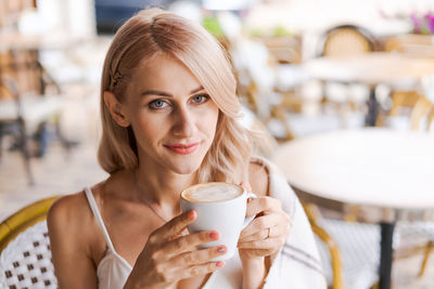 Portrait pretty blonde woman, smiling woman in cozy plaid, sitting in cafe