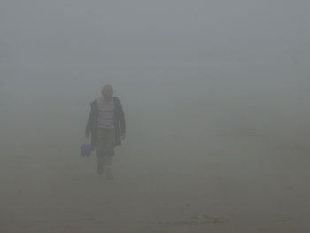 Man walking at beach in foggy weather