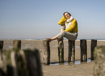 Woman standing at beach against sky