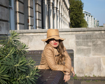 Portrait of young woman standing against brick wall