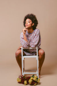 Portrait of young woman using digital tablet while sitting against wall