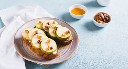 Appetizing sandwiches on rye bread with arugula, pear, honey and nuts on a plate web banner