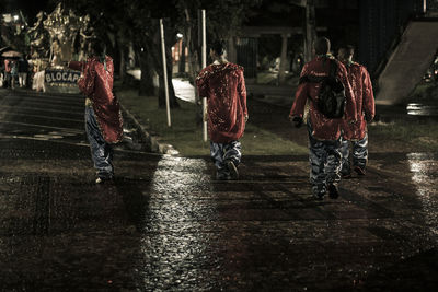 Rear view of people walking on wet street during rainy season