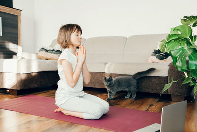 Cute caucasian girl doing yoga at home online in the living room. children are athletes. relaxation