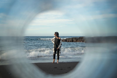 Woman standing at beach against sky