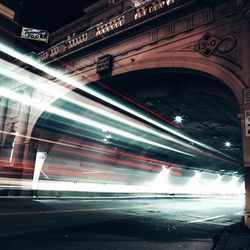 Light trail coming out of arch bridge at night