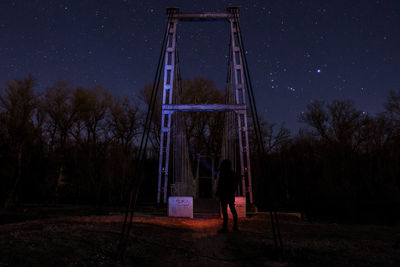 Rear view of person standing on field against sky at night