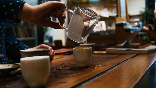 Cropped hands preparing coffee on table in cafe