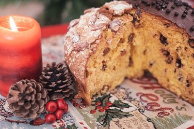 Close-up of bread and pine cone with lit candle on table