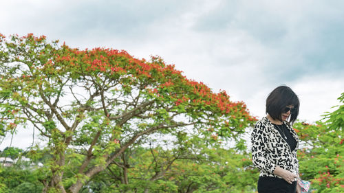 Rear view of woman standing against phoenix trees