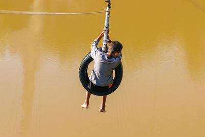 Rear view of man hanging on rope against wall