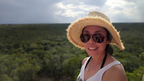 Portrait of smiling woman wearing sunglasses and hat against sky