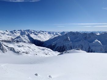 Scenic view of snowcapped mountains against blue sky