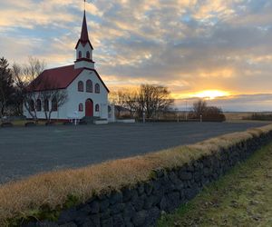 Church on field by building against sky during sunset