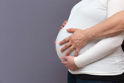 Midsection of woman holding hat against gray background