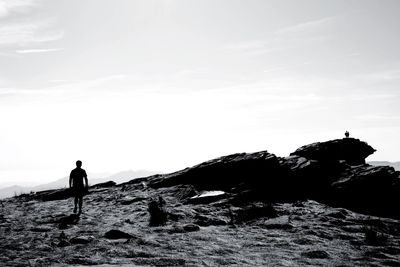 Silhouette of woman standing on mountain against sky