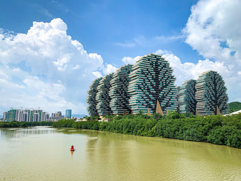 Scenic view of river by buildings against sky