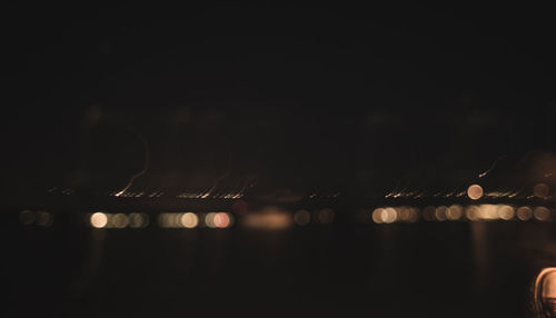 Defocused image of illuminated lights against sky at night