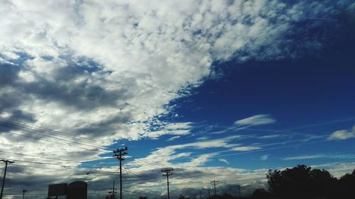 Low angle view of power lines against cloudy sky