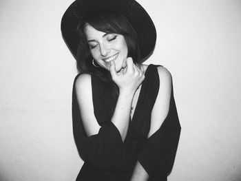 Smiling young woman wearing hat while standing against white background