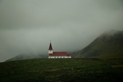 Christian church on green hill against foggy sky