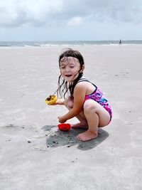 Cute girl playing on sand against sea at beach