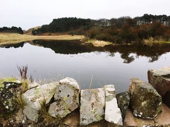 Close-up of rocks by lake against sky