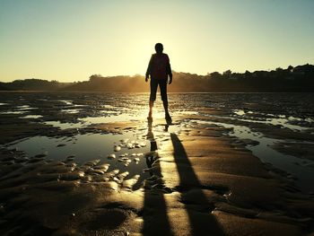 Rear view of man standing on beach against sky