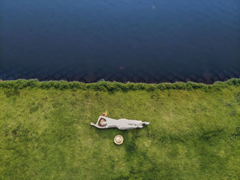 Caucasian young woman in white dress laying on the grass on the shore edge. up side photo. 